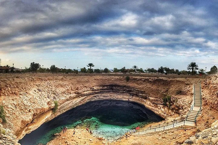 Weitblick auf Bimmah Sinkhole mit seinem leuchtend türkisfarbenen Wasser und der umgebenden Landschaft.